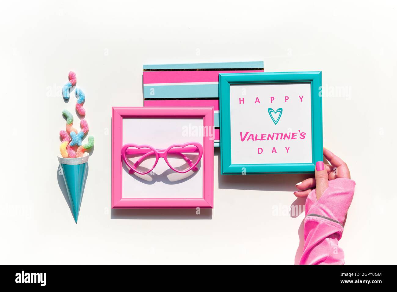 Happy Valentines day. Collection of vibrant objects and sweets in pink and mint green.Top view, flat lay. Chocolate, candy. Notebook, frame in hand. F Stock Photo