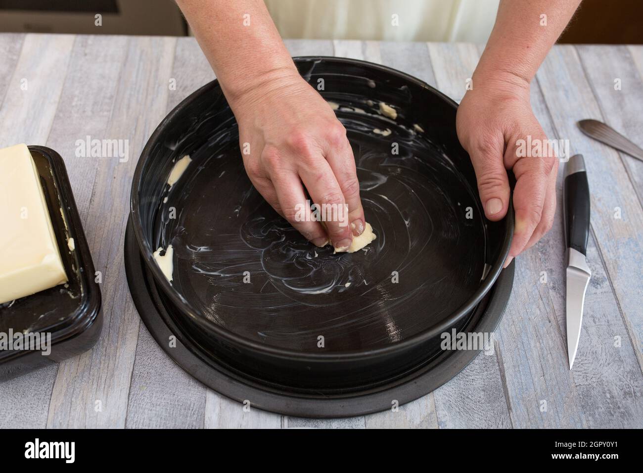 Step by step the process of making sour cream pie dough. Female hands prepare a baking dish, grease with butter and sprinkle with semolina. Baking con Stock Photo