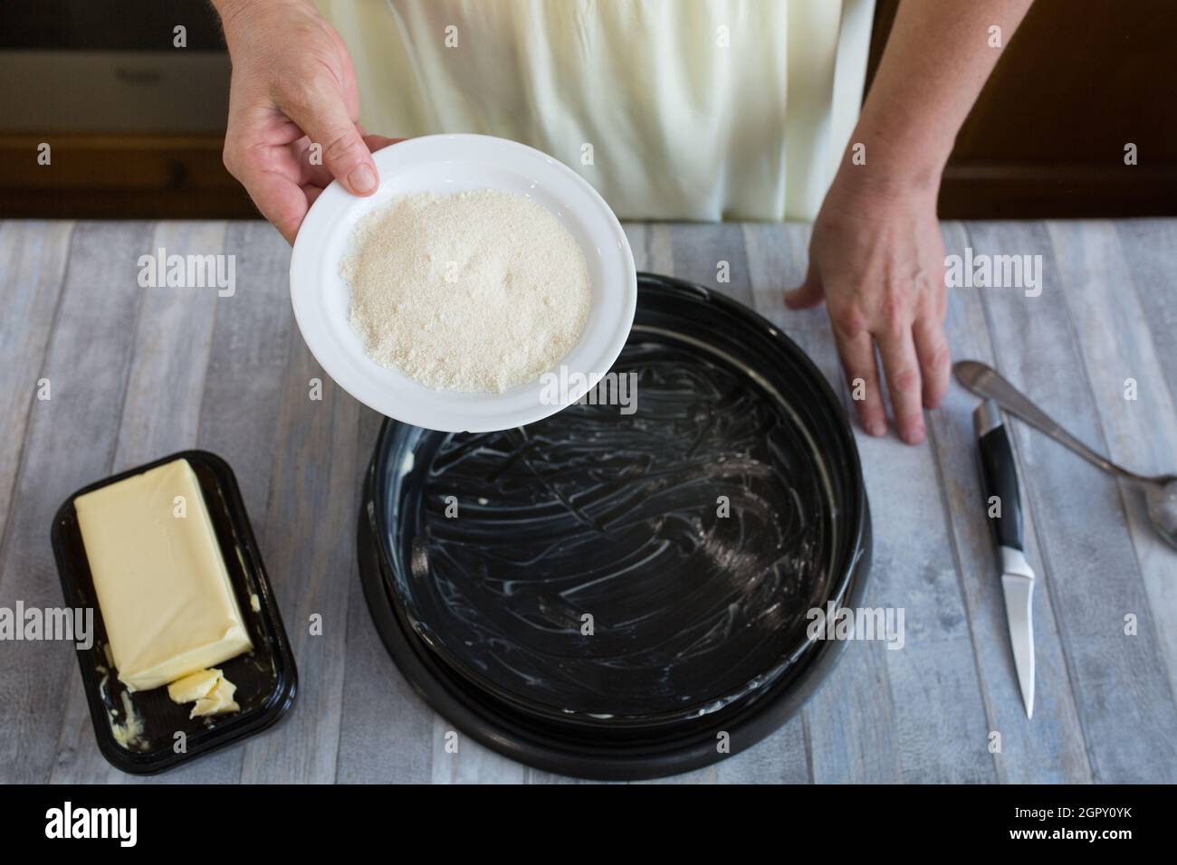 Step by step the process of making sour cream pie dough. Female hands prepare a baking dish, grease with butter and sprinkle with semolina. Baking con Stock Photo