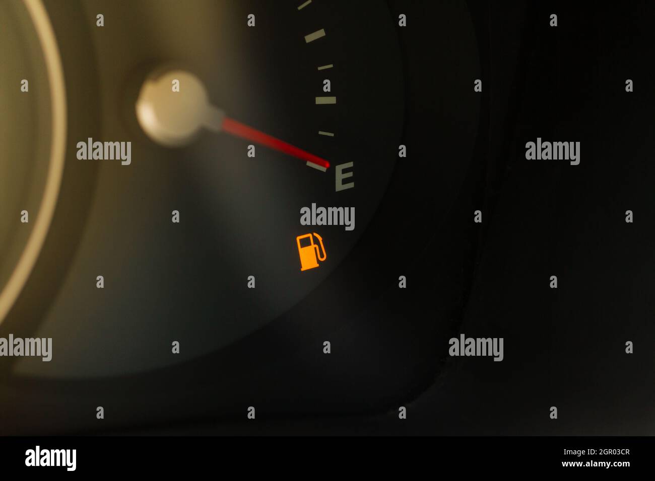 Analog fuel gauge showing warnin light about empty tank. Close up view of low fuel tank warning. Stock Photo