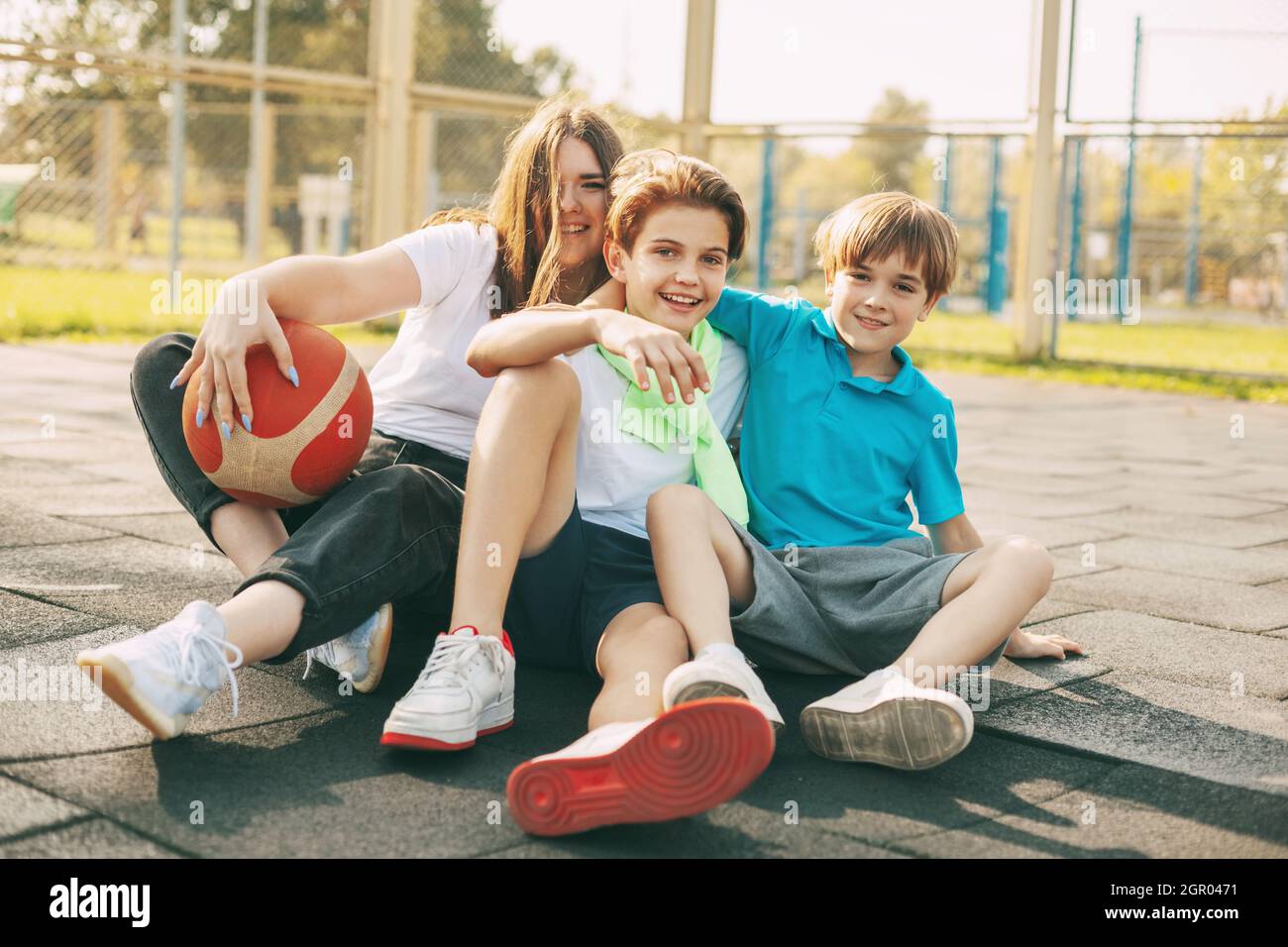Cheerful High School Students Sit On The Basketball Court, Relax After