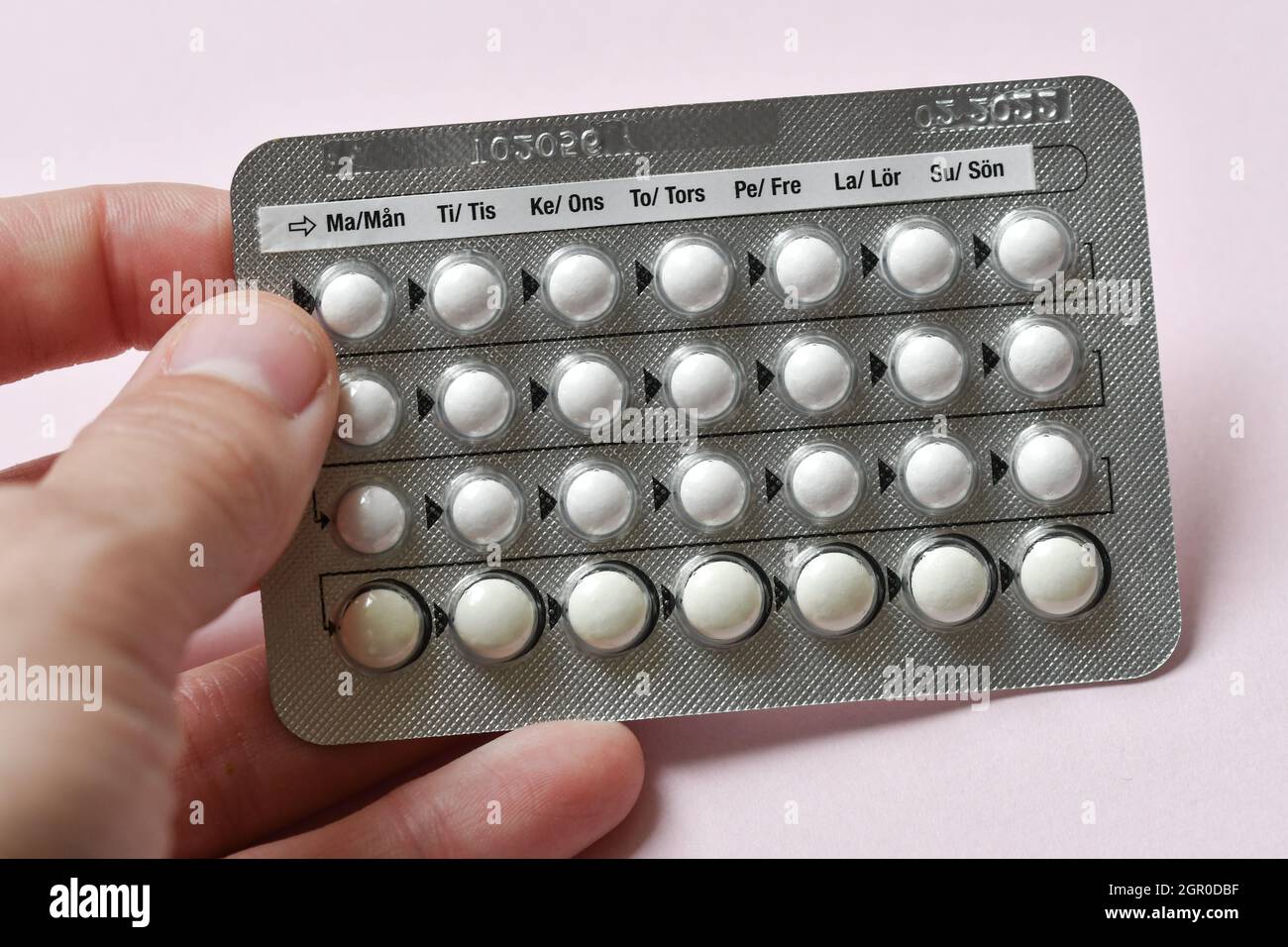 A woman holding a full chart of birth control pills on pink background Stock Photo