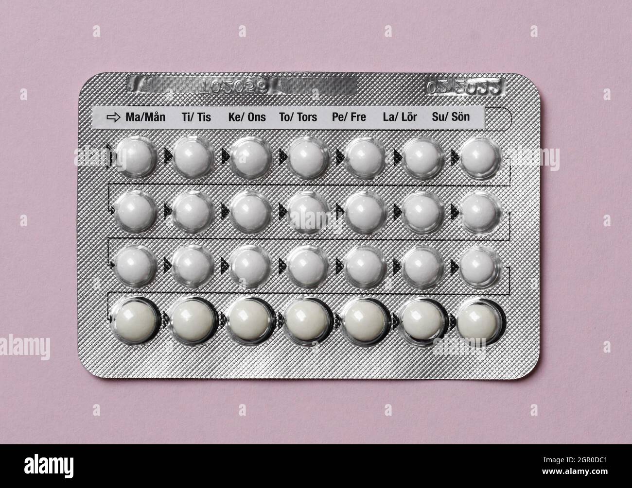Overhead of a full chart of birth control pills on pink background Stock Photo