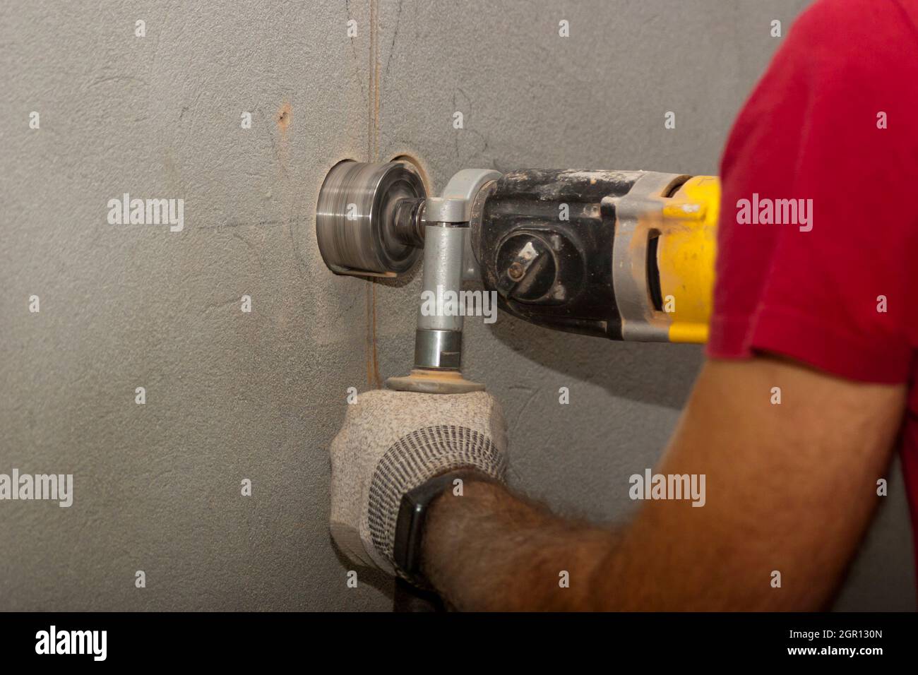 The technician uses a drill to drill a hole in the wall to install an