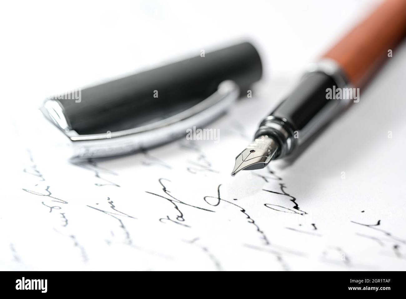 Nostalgic fountain pen and cap on an illegible handwritten letter or manuscript, close-up with selected focus and narrow depth of field Stock Photo