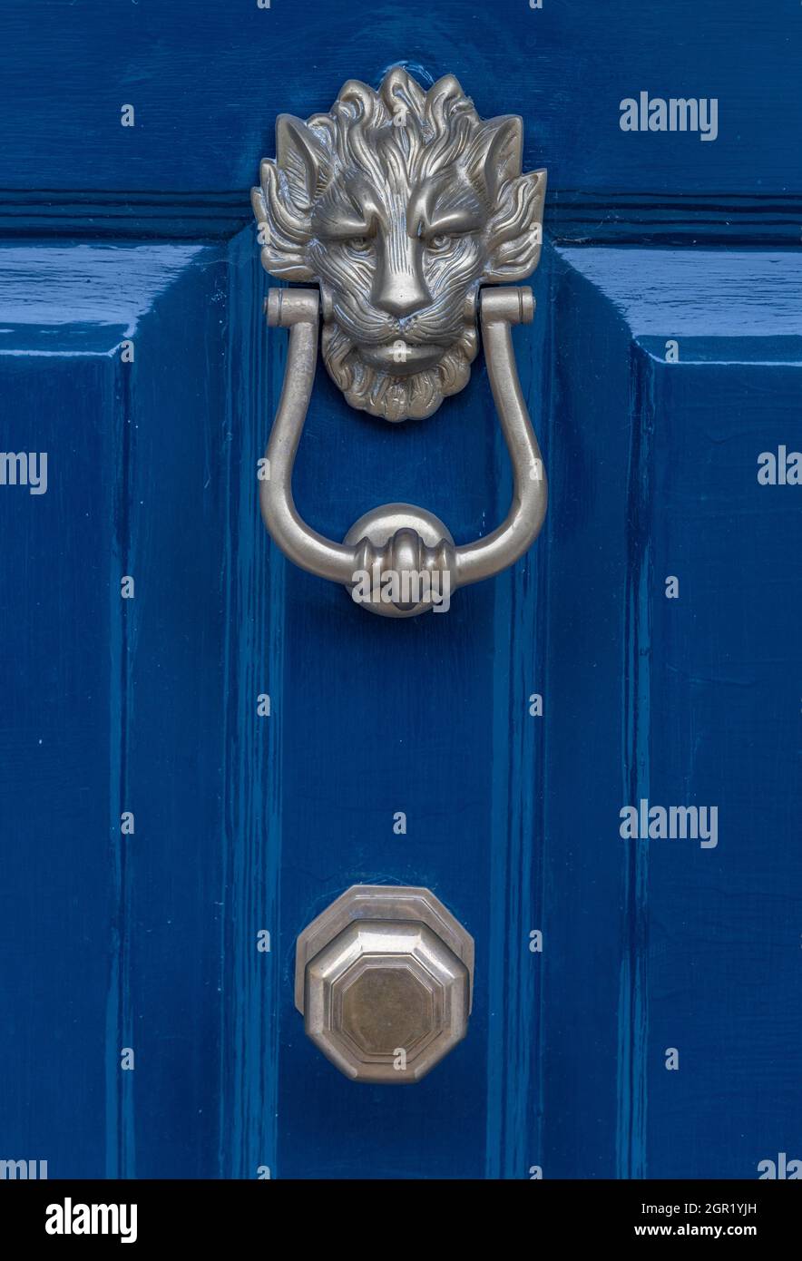 traditional antique brass door knocker and knob on a blue painted