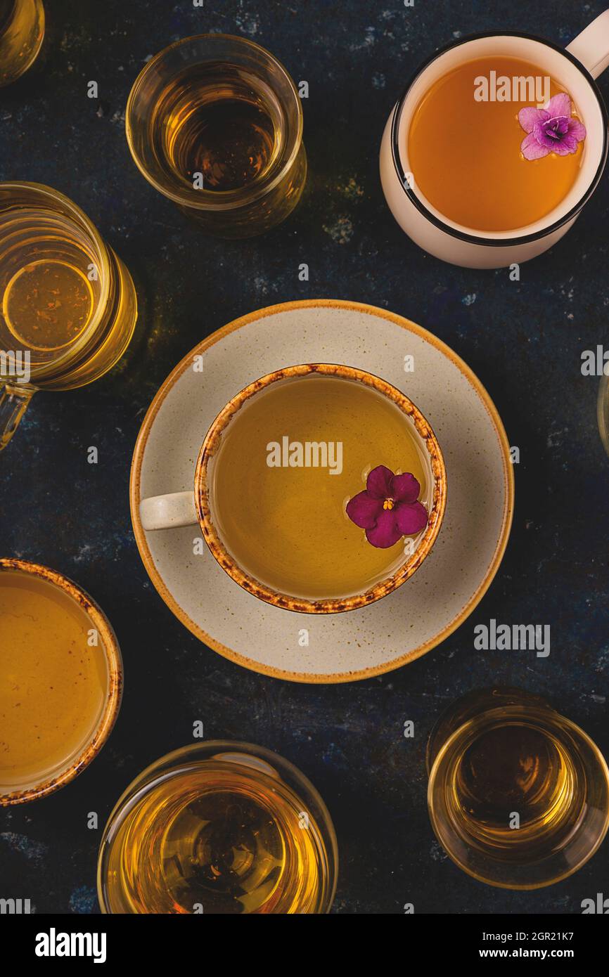 Many Different Cups Of Tea With Violet Flowers On Dark Blue Background