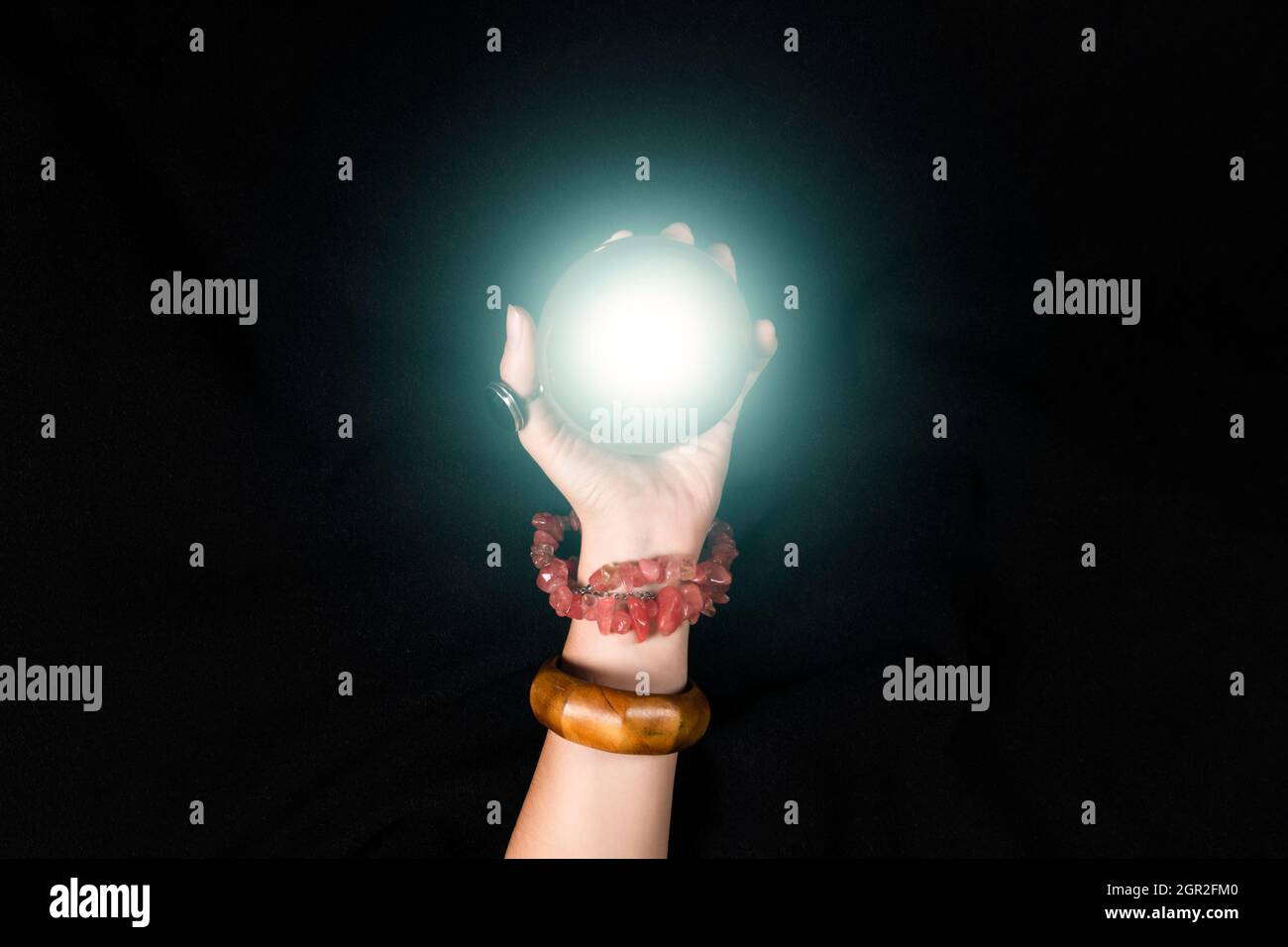 Fortune teller or witch hand and a glowing magic ball isolated on black ...