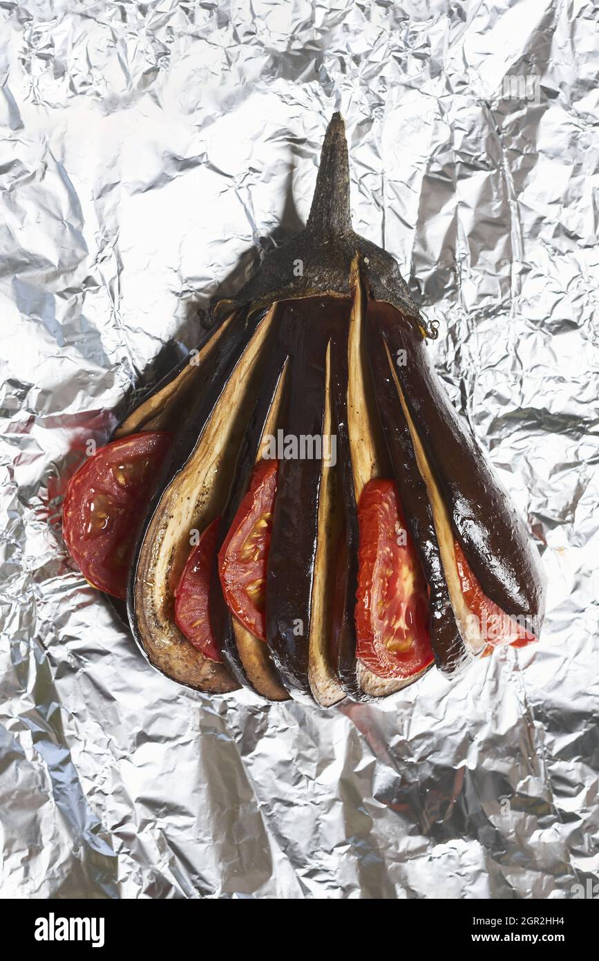 Vertical shot of grilled eggplants with tomatoes on the foil Stock