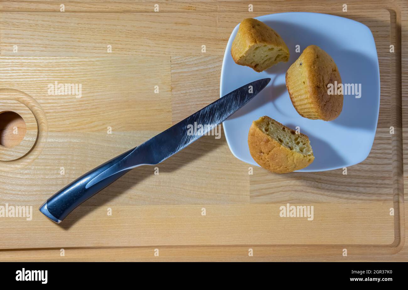 Freshly baked muffins cut with a knife on a square plate on a wooden background. High quality photo Stock Photo