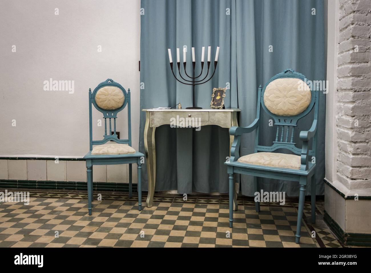 Vintage interior with two chairs, a small table, and a candle holder. Stock Photo