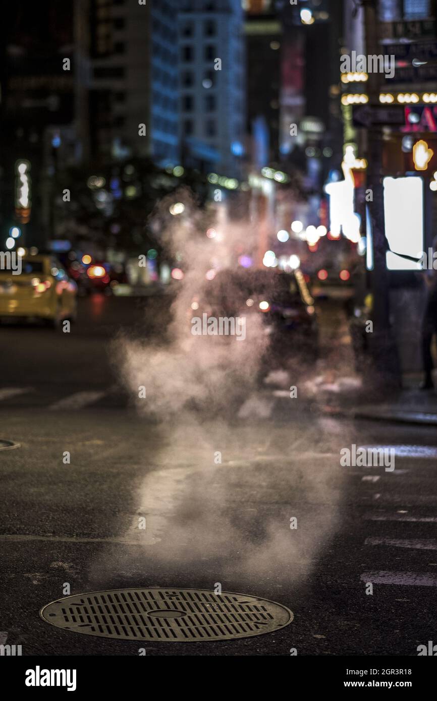 Steam coming out from a manhole on the street at night Stock Photo