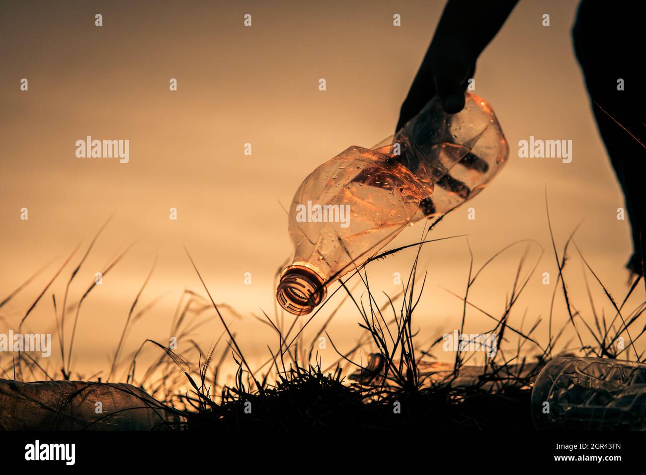Cropped Hand Of Person Holding Plastic Bottle Against Sky Stock Photo