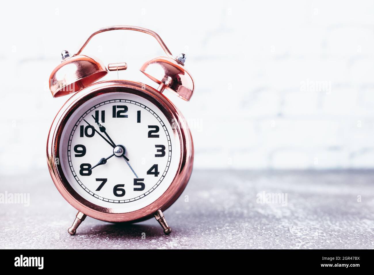 Vintage Bell Alarm Clock On Blurred White Brick Background With Copy
