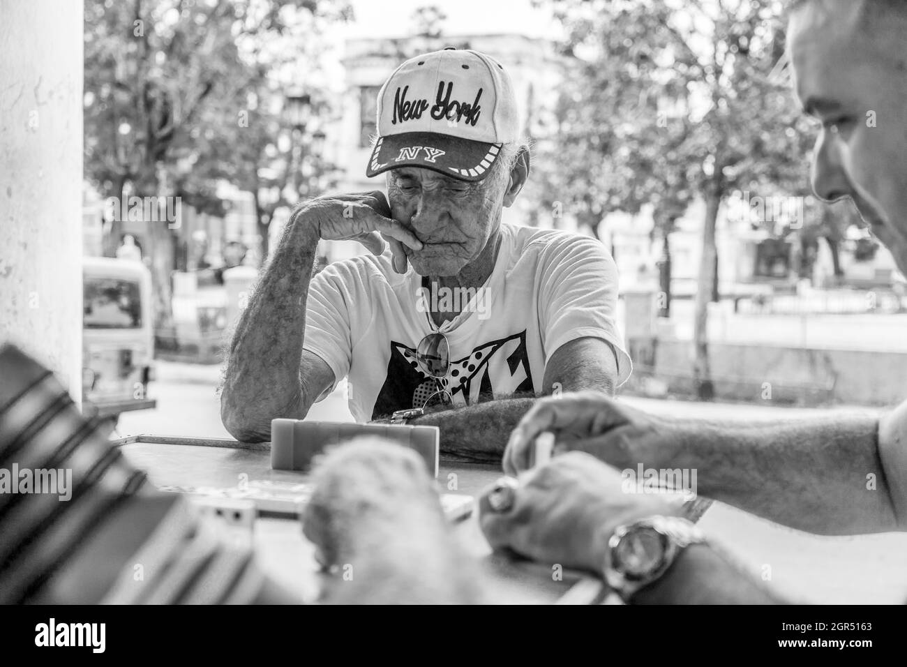 HABANA, CUBA - Oct 25, 2019: A grayscale closeup of the older people sitting at the table outdoors. Havana, Cuba. Stock Photo