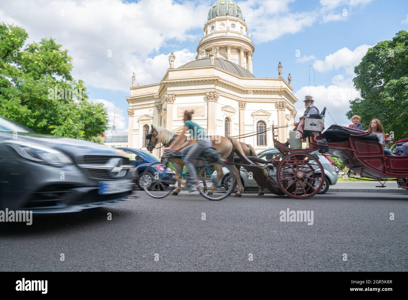 Berlin, Germany - September 25, 2017: Traditional style building with brass dome and gold statue with three modes of transport blurred in motion passi Stock Photo