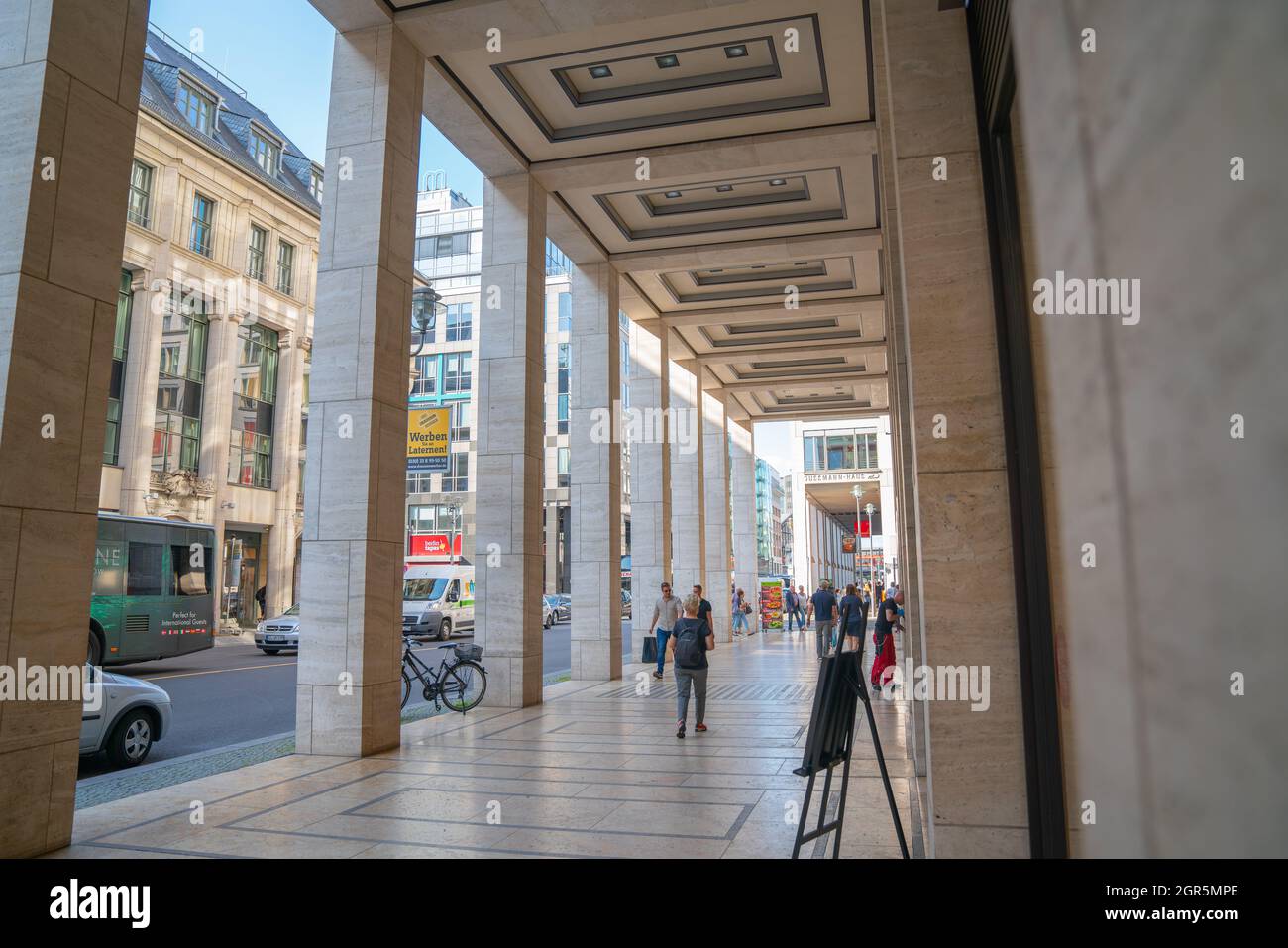 Berlin, Germany - August 28 2017; Portico of retail shops on city street with people blurred in motion walking along. Stock Photo