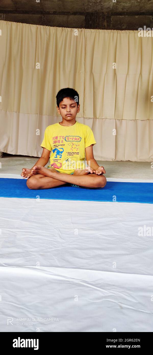 Portrait Of A Smiling Boy Sitting Lotus Pose On Yoga Mat Stock Photo