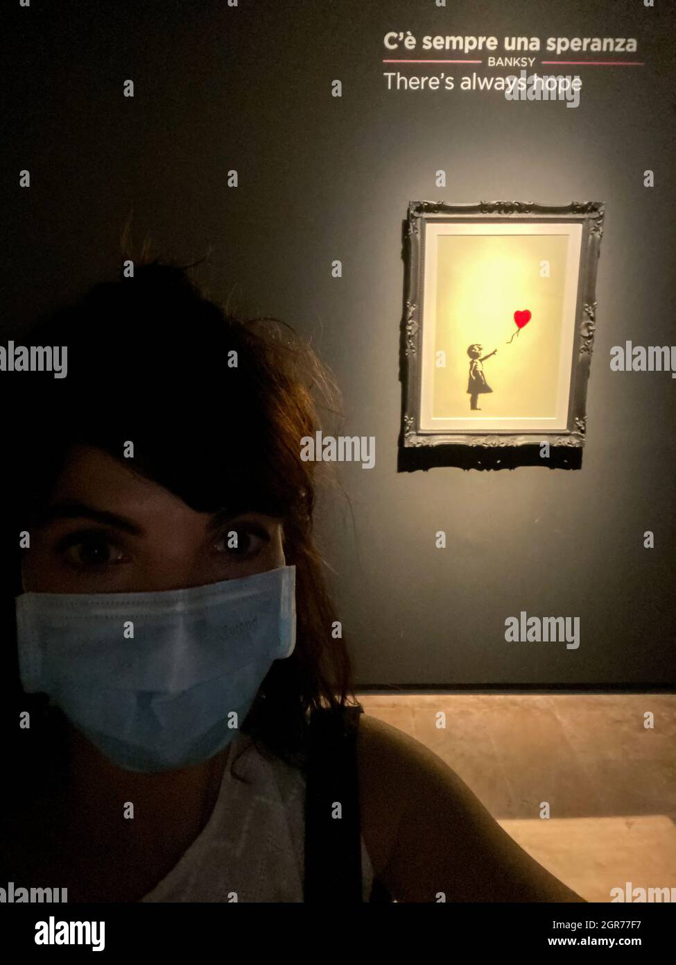 Portrait Of A Woman With Face Mask In A Museum  With Banksy Artpiece Girl With The Balloon Stock Photo