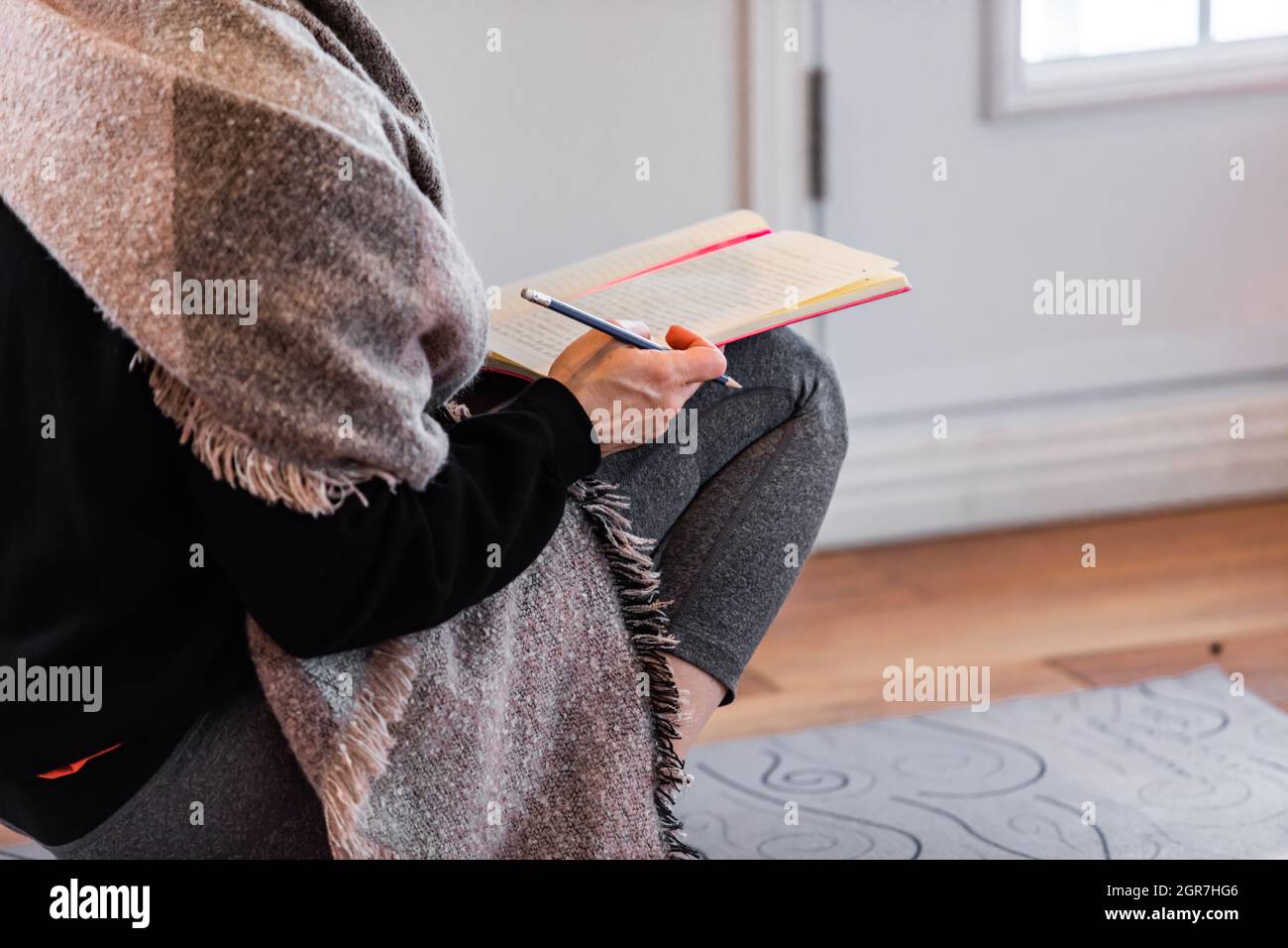 Midsection Of Woman Reading Book At Home Stock Photo