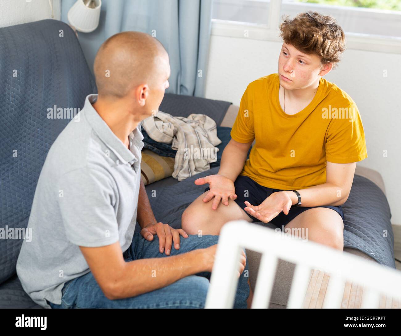 Teenage guy and his father having conversation together Stock Photo