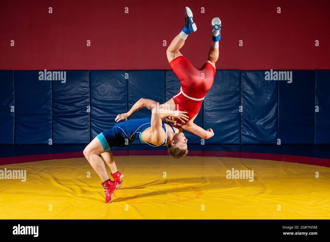 Two Strong Men In Blue And Red Wrestling Tights Are Wrestlng And Making