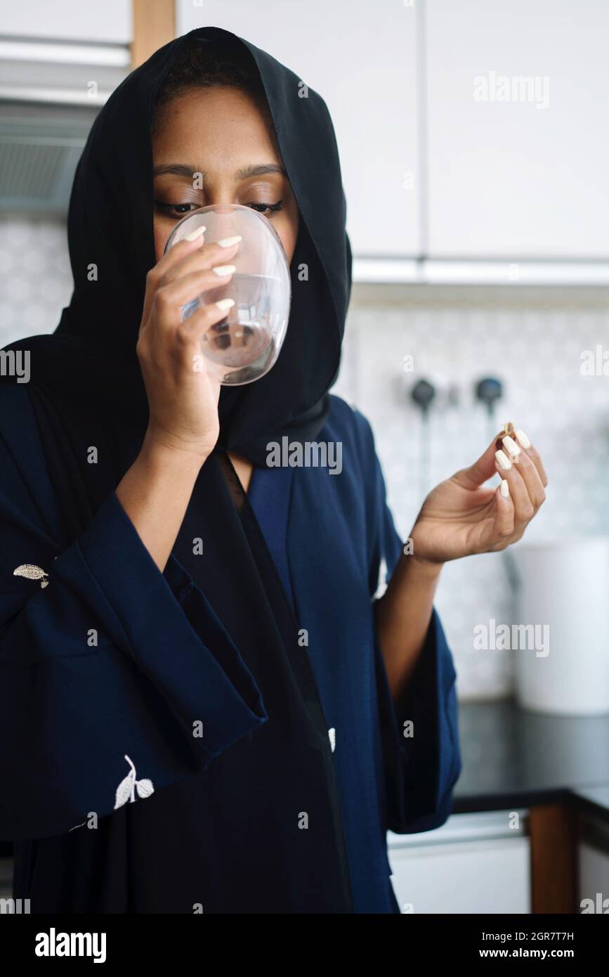 Muslim Woman Wearing Abaya Breaking Fast During Ramadan Eating Dates