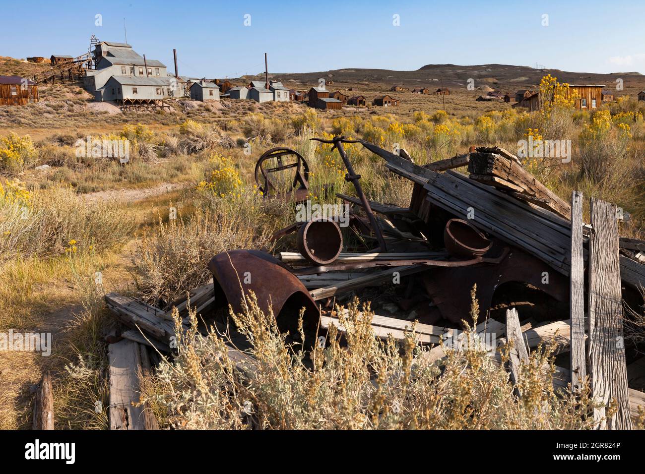 The rusted headlights, fenders, and steering wheel are all that remain an automobile in Bodie. Stock Photo