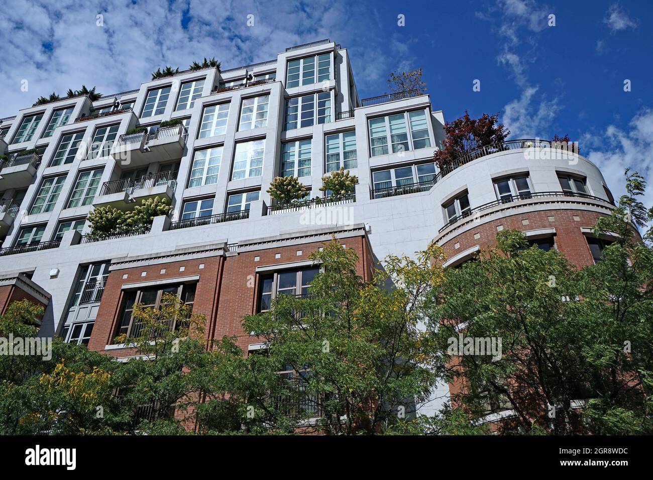 apartment building surrounded by trees, with plants on balconies and roof, which is good for the environment Stock Photo