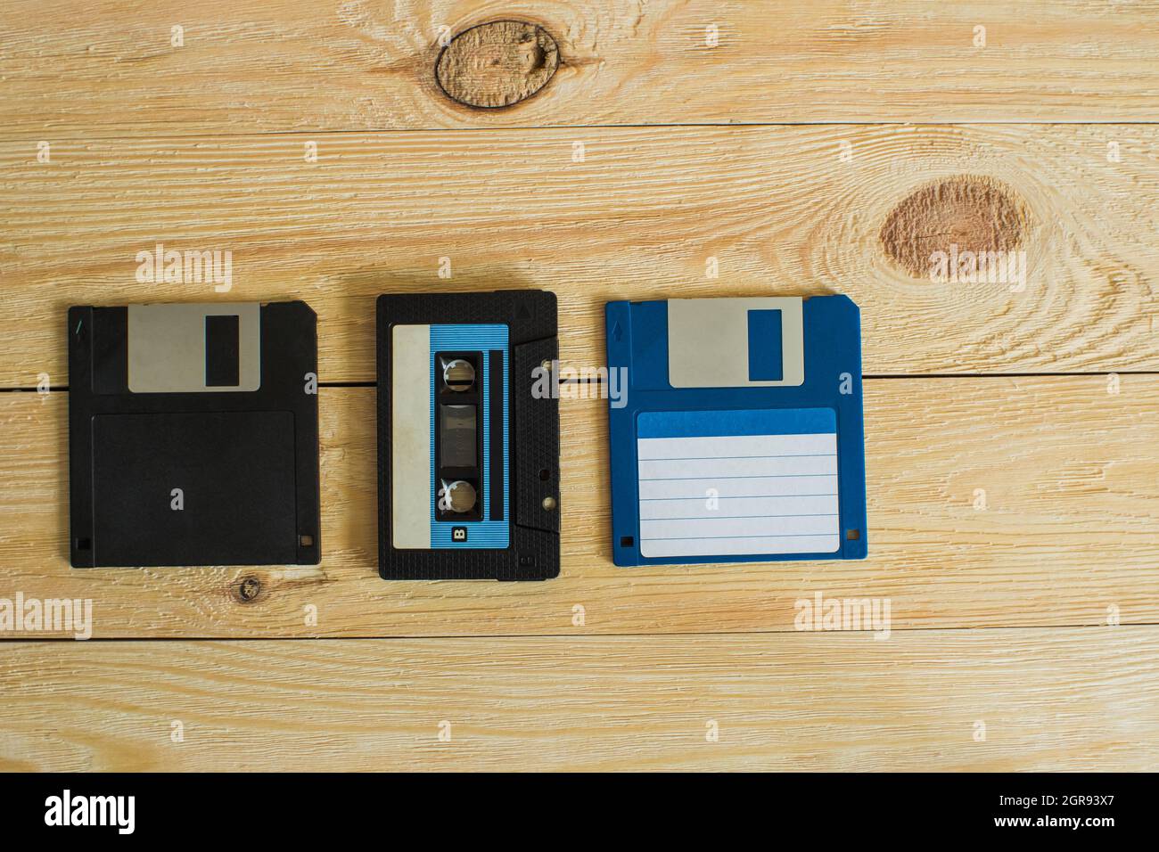 On A Wooden Background With Knots Is An Audio Cassette And Two Floppy Disks Stock Photo