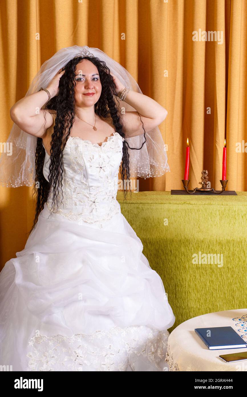 A Jewish Bride In A White Wedding Dress Wears A Veil Before The Chuppah