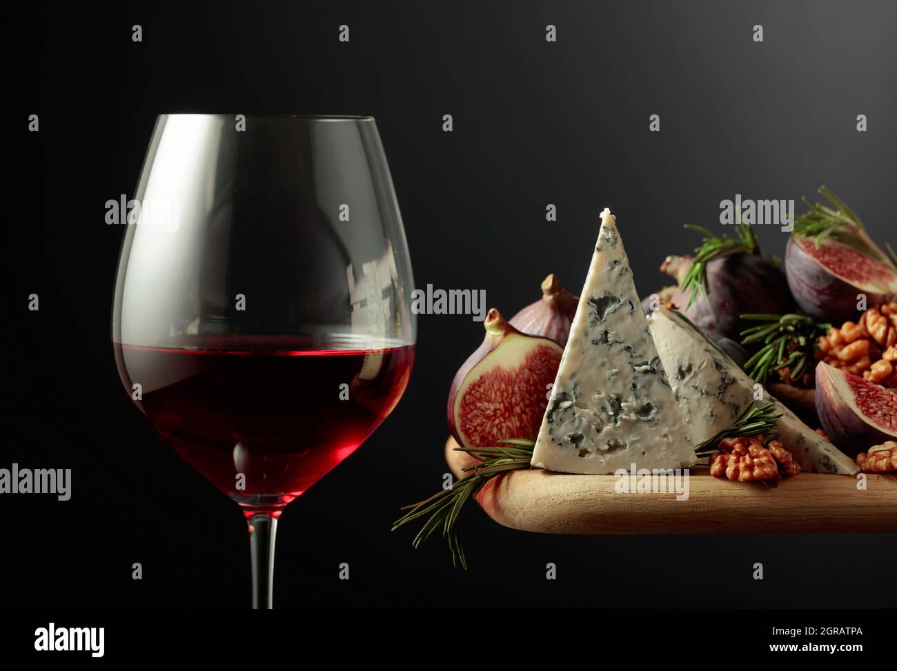 Glass of red wine with blue cheese, figs, walnuts, and rosemary Stock