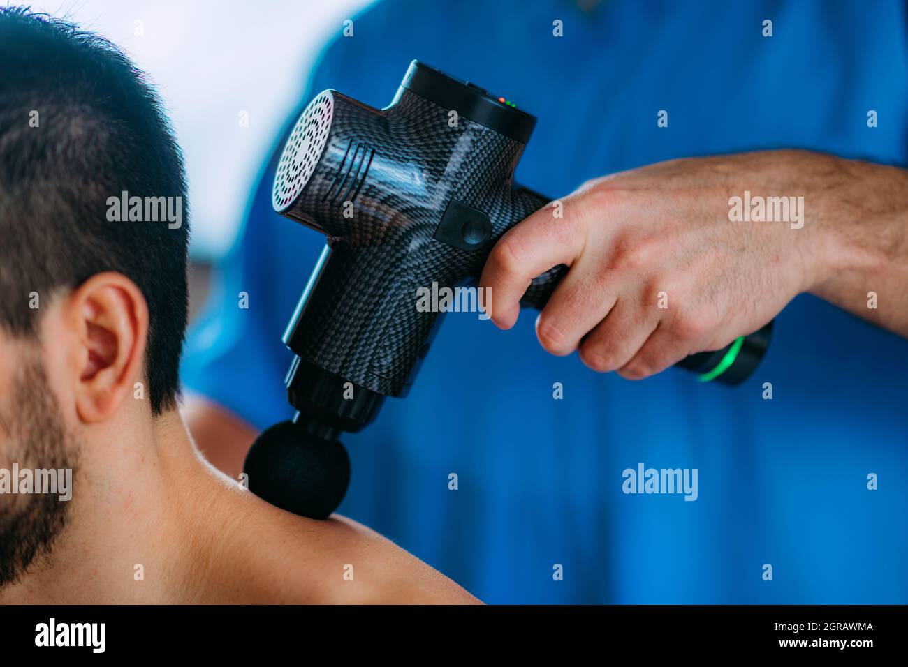 Therapist Treating Trapezius Muscle Injury On Athlete With Massage Gun