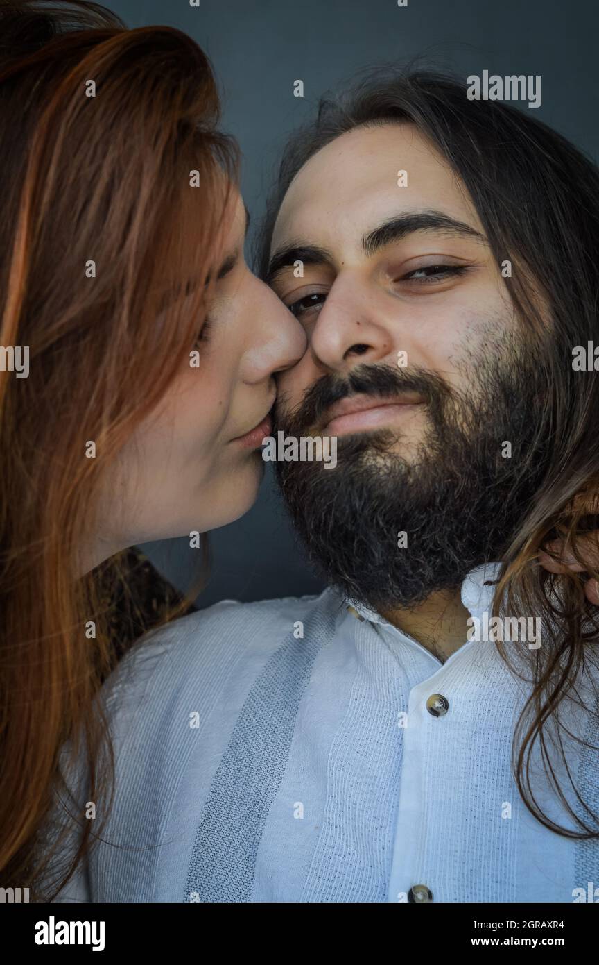 Portrait of a young couple where a long red haired woman kisses the