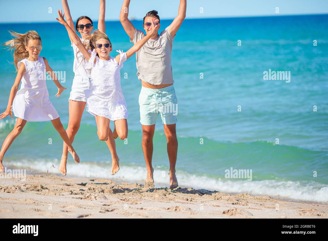Cheerful Family Jumping On Beach With Arms Raised Stock Photo Alamy