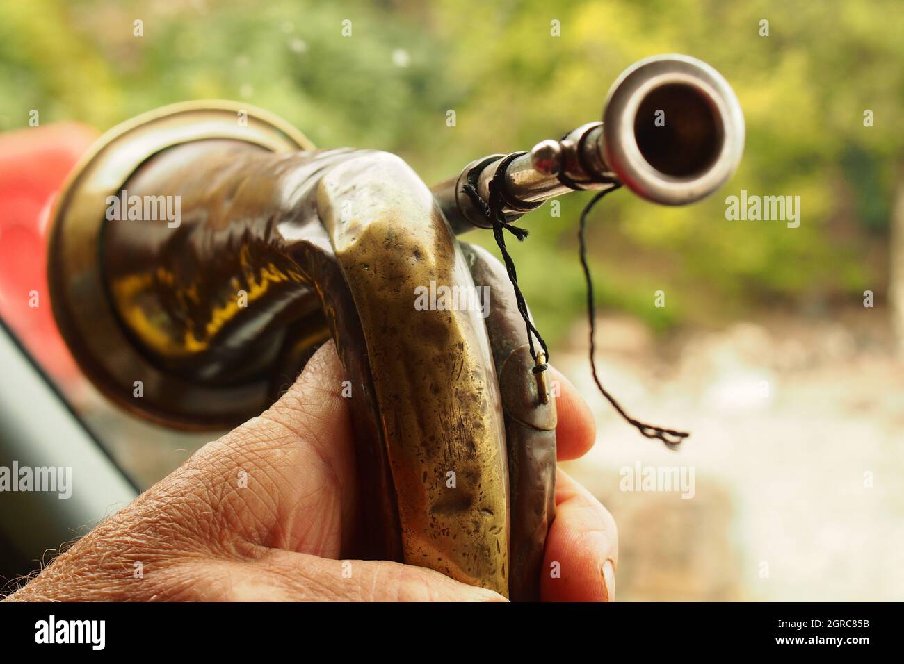 A close up of a man's hand holding a Boys Brigade bugle made of copper