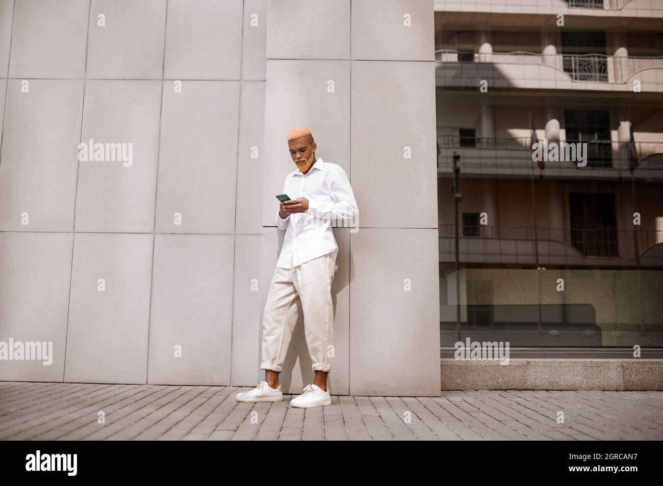 A picture of a tall dark-skinned man in white clothes on a urban background Stock Photo