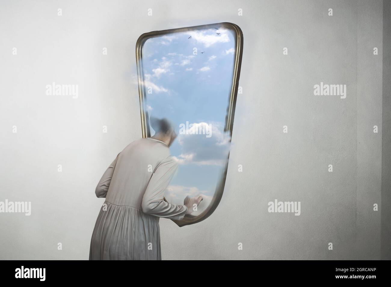 woman in search of freedom escapes from a mirror that contains a window to the sky Stock Photo