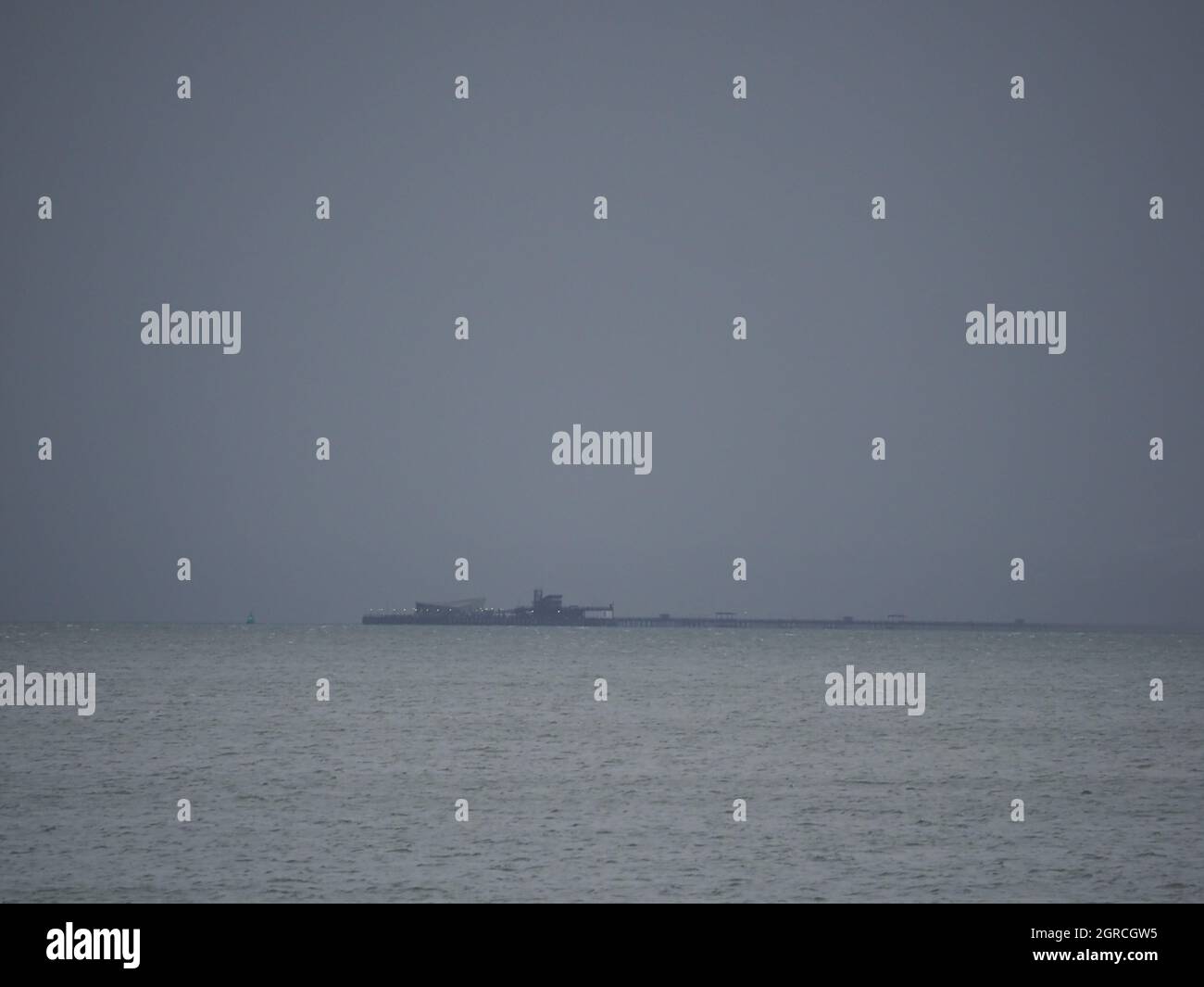 Sheerness, Kent, UK. 1st October, 2021. UK Weather: dark grey rain clouds on the first day of October in Sheerness, Kent. The end of Southend's 1 mile long pleasure pier about to disappear beneath a rain shower. Credit: James Bell/Alamy Live News Stock Photo