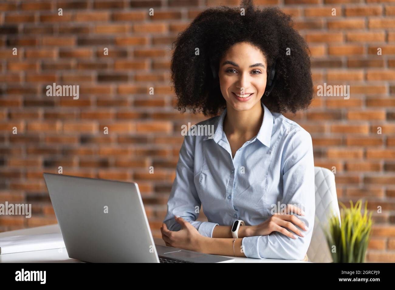 Successful biracial woman wearing smart casual shirt stands in confident pose with arms crossed, confident mixed-race female entrepreneur in home office looks at the camera Stock Photo