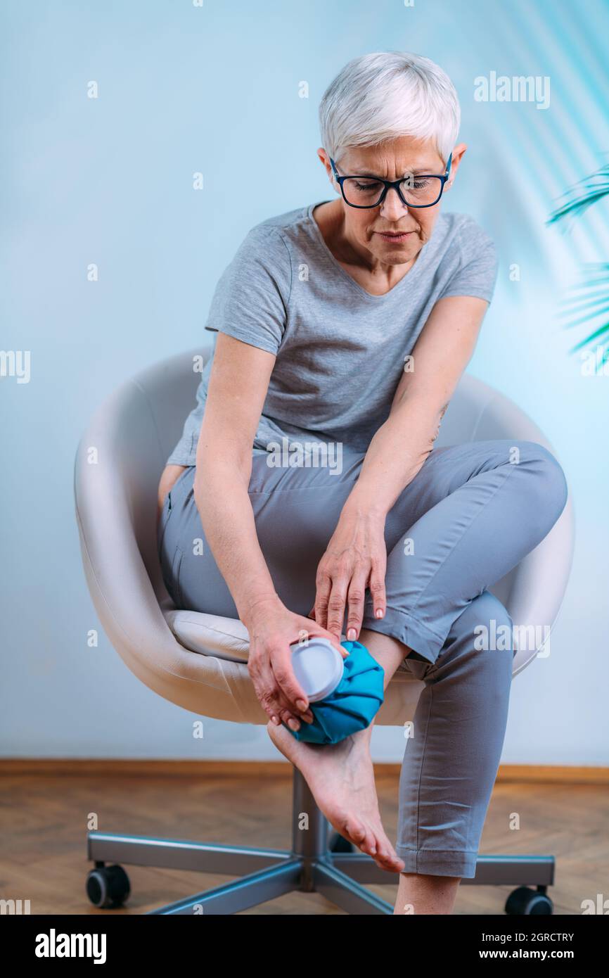 Ankle Pain Treatment. Senior Woman Holding Ice Bag Compress On A Painful  Ankle Joint Stock Photo - Alamy