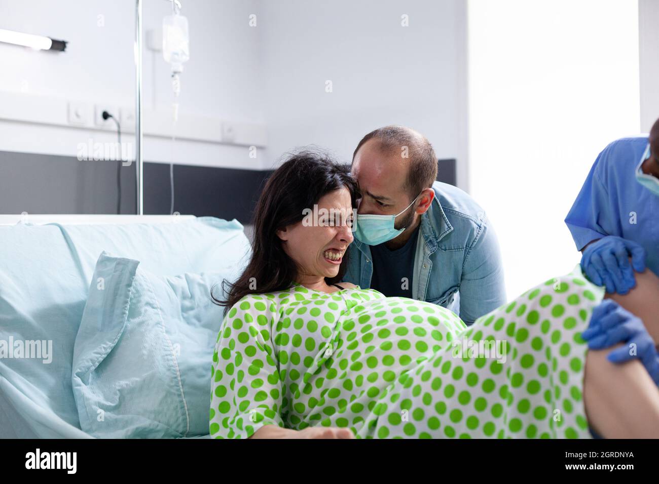 https://c8.alamy.com/comp/2GRDNYA/pregnant-woman-pushing-for-childbirth-having-contractions-in-hospital-ward-bed-young-adult-giving-birth-to-baby-with-man-obstetrician-and-african-american-nurse-at-medical-clinic-2GRDNYA.jpg