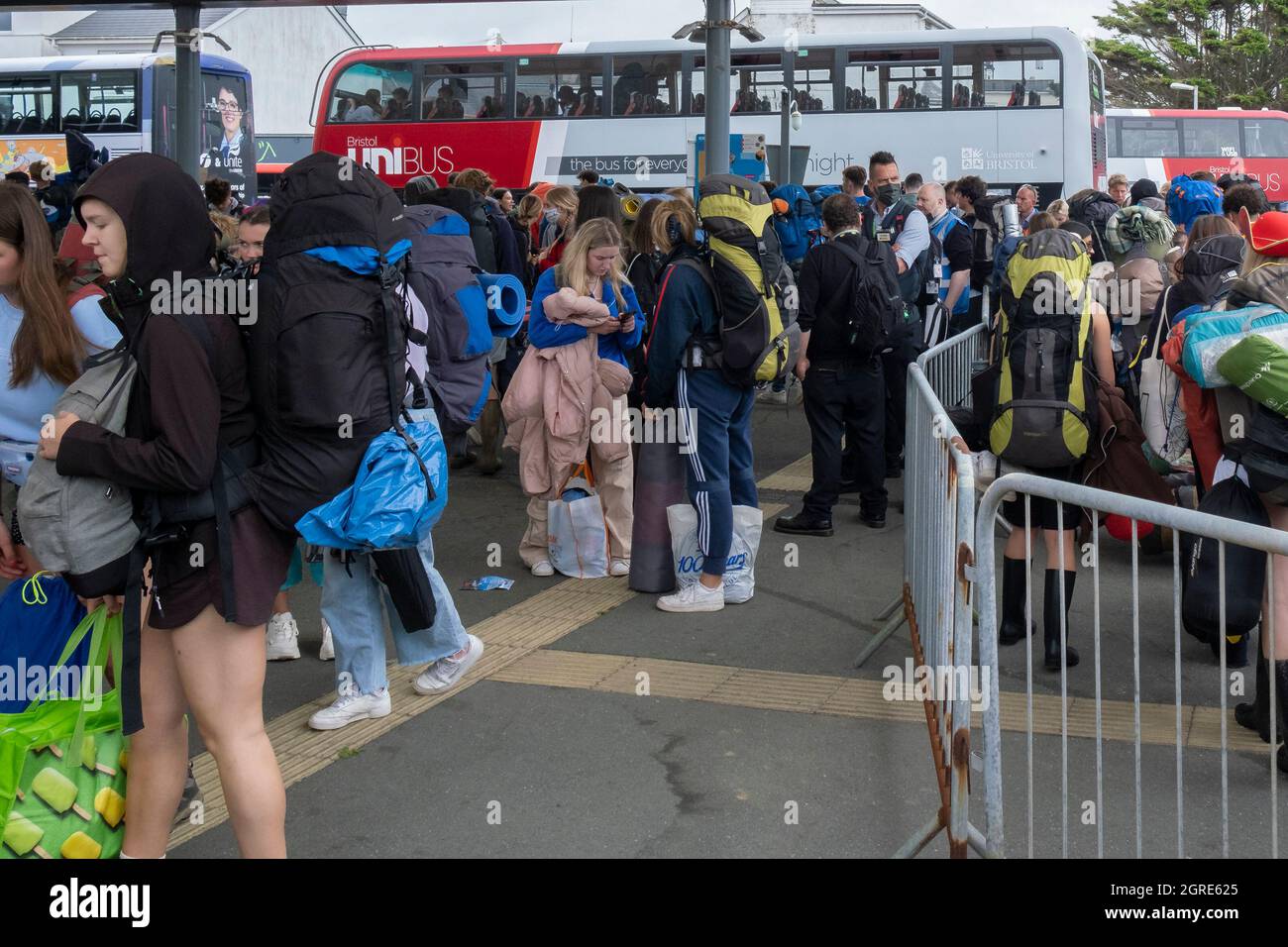 Young people carrying heavy rucksacks and queueing for buses to take them to the opening day of The Boardmasters Festival in Cornwall. Stock Photo