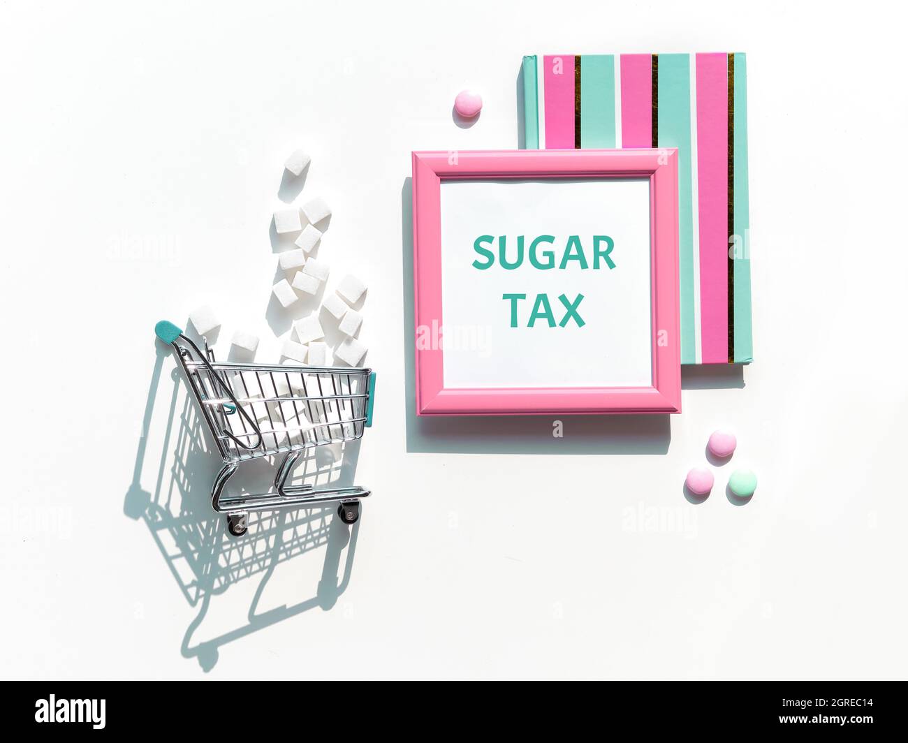 Text Sugar Tax. Various tasty snacks in pastel colors, pink, mint green, on white background