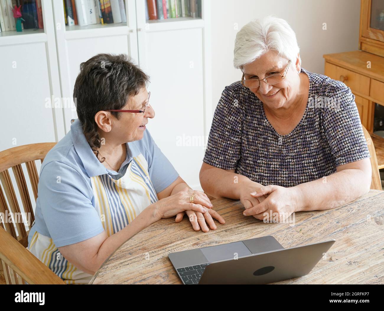 High Angle View Of Senior Friends Sitting With Laptop At Table Stock Photo