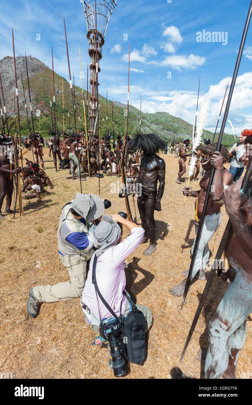 Indonesia, Papua, city of Wamena, asian tourists photographing local tribes. Baliem Valley Cultural Festival, every August, tribes come together to perform ancestral war scenes, parade and dance in traditional clothes Stock Photo