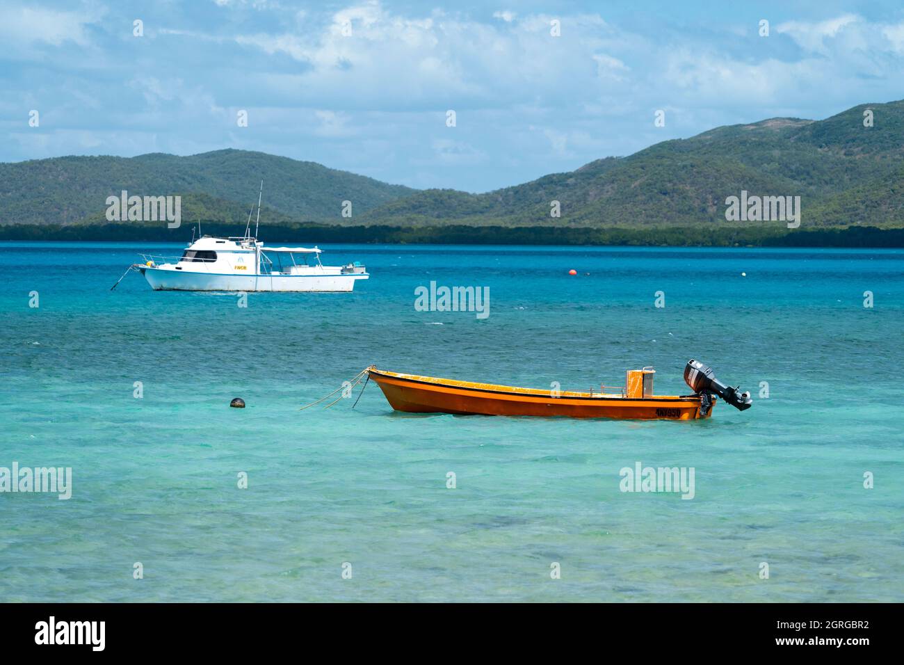 Orange dingy and white fishing boat anchored of Thursday Island, Torres Straits, Queensland Australia Stock Photo