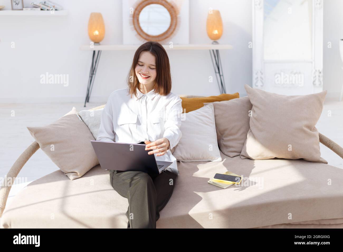 Young smiling woman in business style clothes works in laptop at home Stock Photo