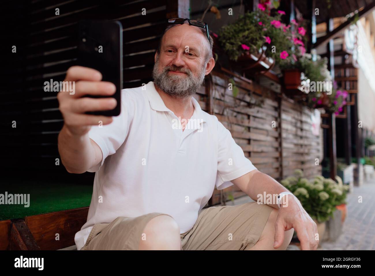 Funny old man taking selfie by cellphone. Summer holiday Stock Photo