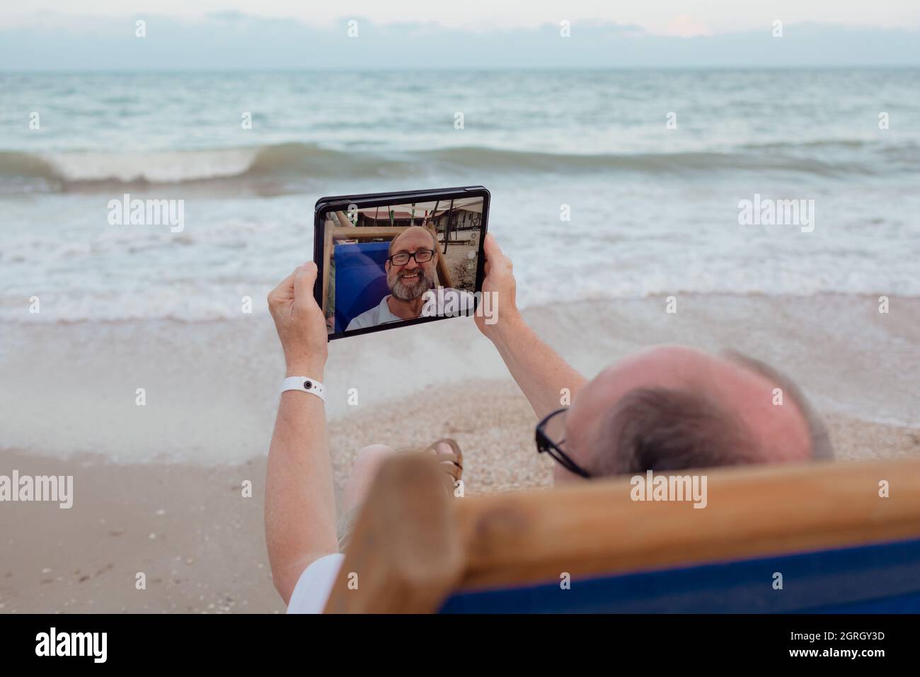 Funny old man taking selfie by tablet. Summer holiday Stock Photo